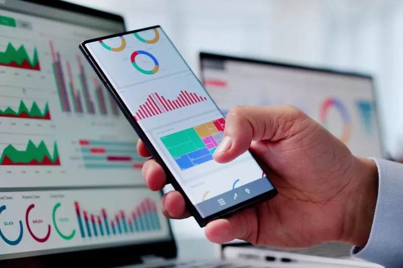 Mann schaut auf Smartphone mit Diagramm